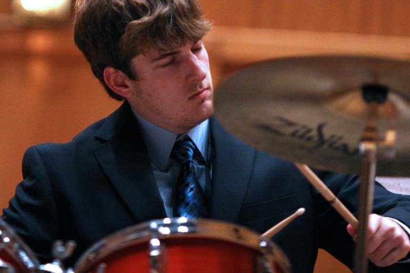a man in a suit playing a drum set