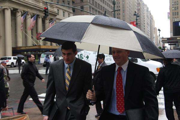 men in suits walking under an umbrella