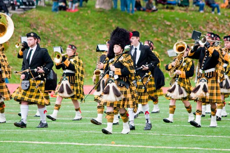 a group of people in yellow and black tartan outfits playing instruments