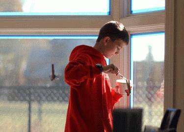 a boy in a red hoodie holding a cup with a spoon