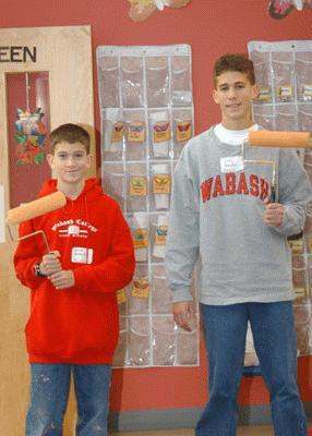 a couple of boys holding paint rollers