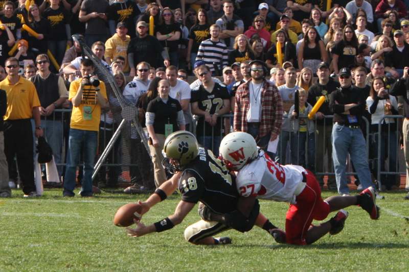 a football player falling down to the ground with another football player in the back