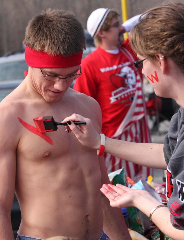 a man with red headband and glasses painting his chest with paintbrush