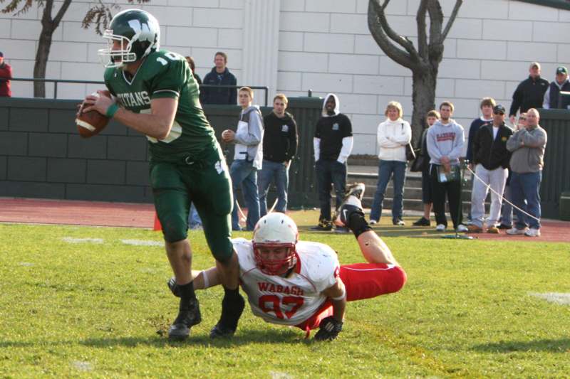 a football player falling off the ground while another player is trying to catch him