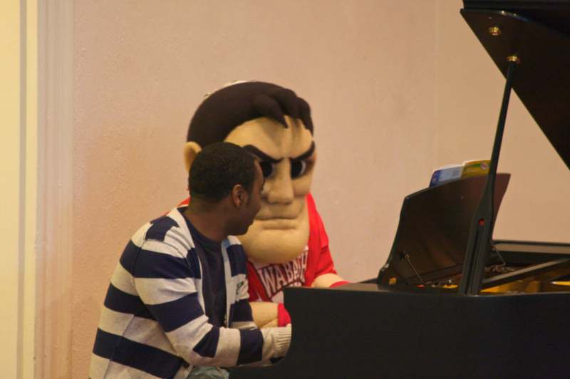 a man sitting at a piano with a person in a garment