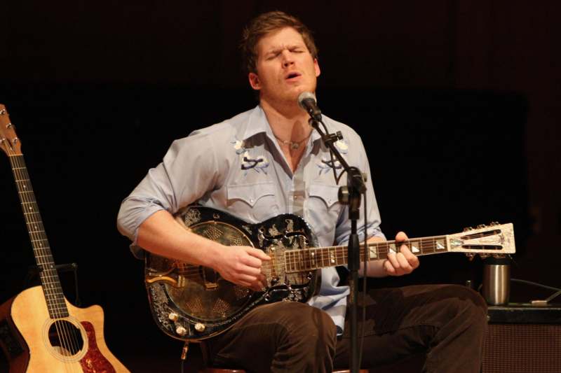 a man playing guitar and singing into a microphone
