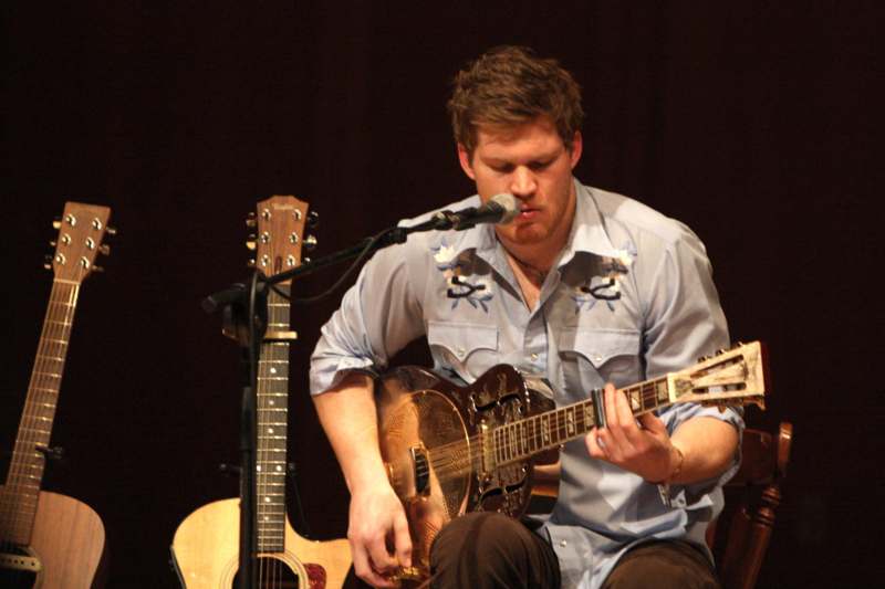 a man playing guitar and singing into a microphone