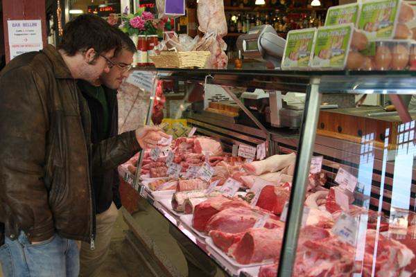 a man looking at meat in a butcher's display case