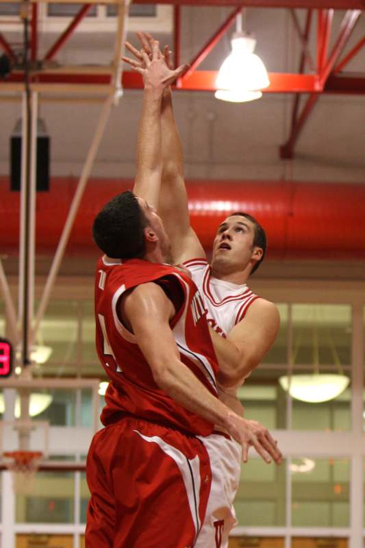 a basketball player in red and white uniform jumping over a basketball hoop