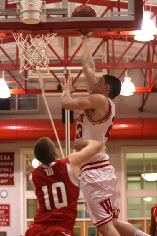 a basketball player in a red uniform jumping to block a basketball hoop