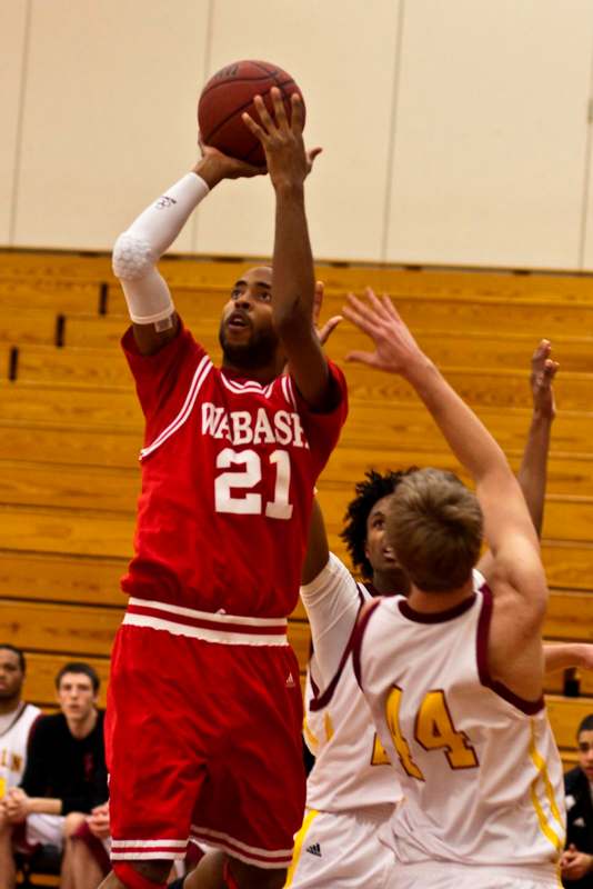 a basketball player in red uniform jumping to shoot a ball