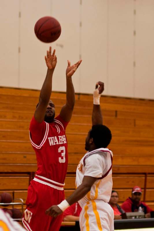 a basketball player in red uniform jumping to shoot a basketball