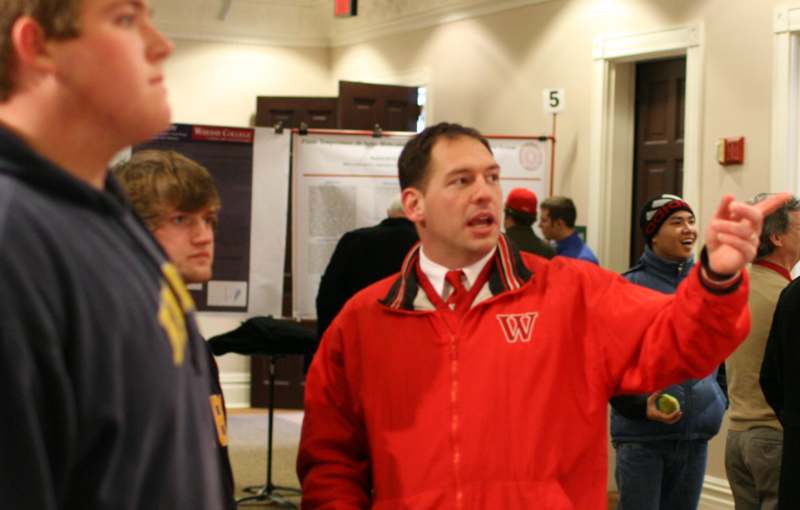 a man in a red jacket talking to a group of people