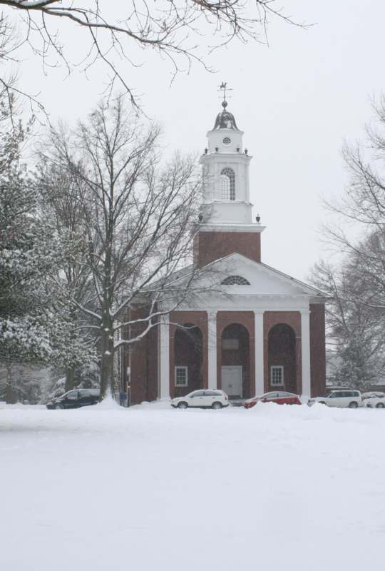 a church with a tower and cars in the snow