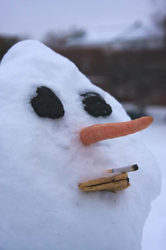 a snowman with a cigarette and carrot nose