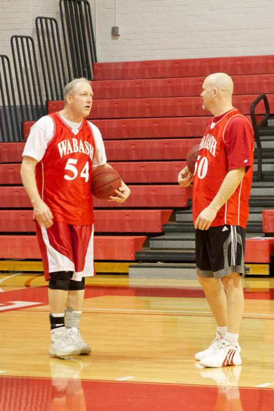a man in a basketball uniform talking to another man in a basketball court