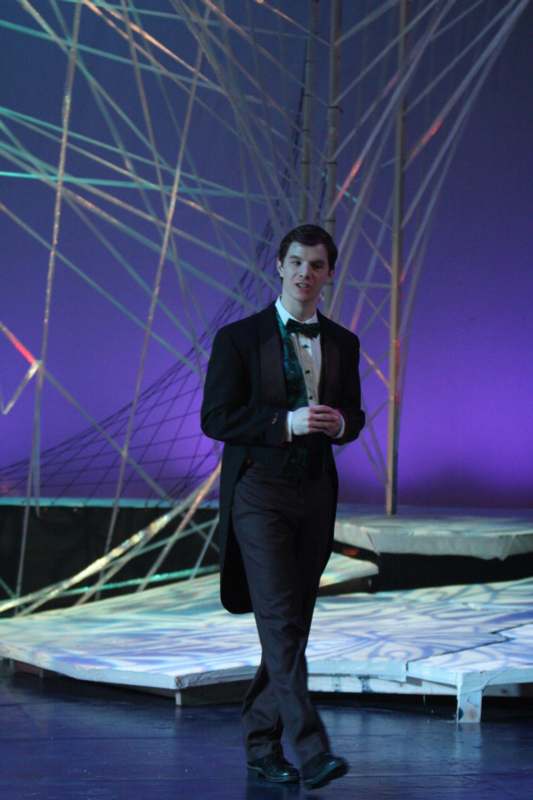 a man in a suit and bow tie walking on a stage