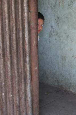 a boy peeking out of a wall