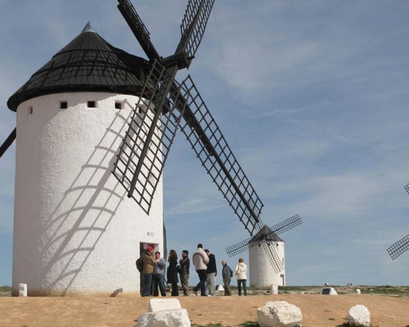 a group of people standing in front of windmills