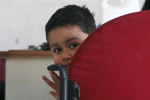 a young boy peeking out of a red chair