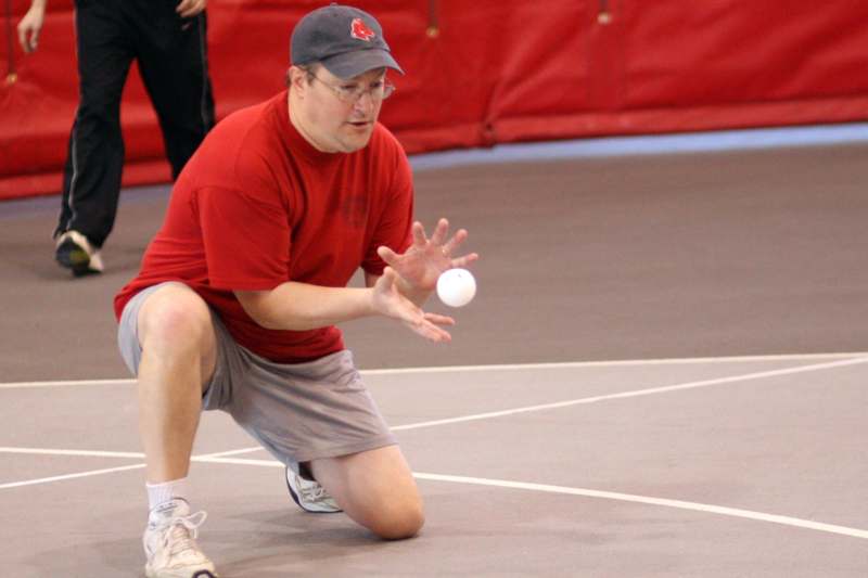 a man in a red shirt and grey shorts holding a white ball