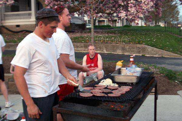 a group of men cooking meat on a grill