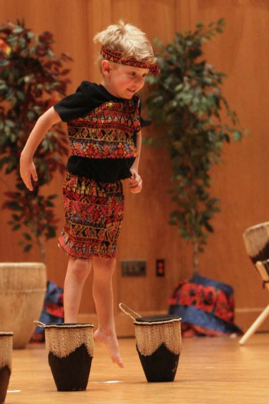 a boy standing on a stack of straw drums