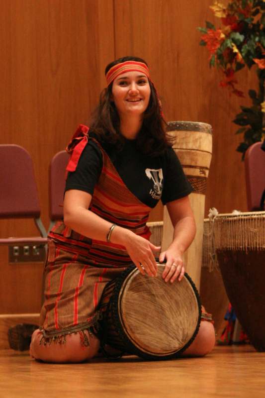 a woman in a garment playing a drum