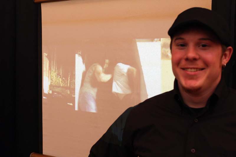 a man smiling in front of a projection screen