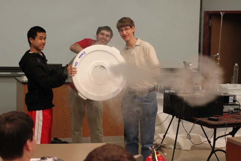a group of men holding a round object with smoke coming out of it