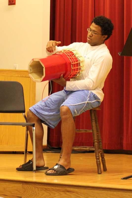 a man sitting on a stool playing a drum