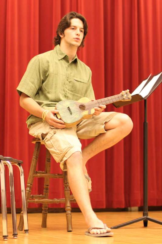 a man sitting on a stool playing a guitar