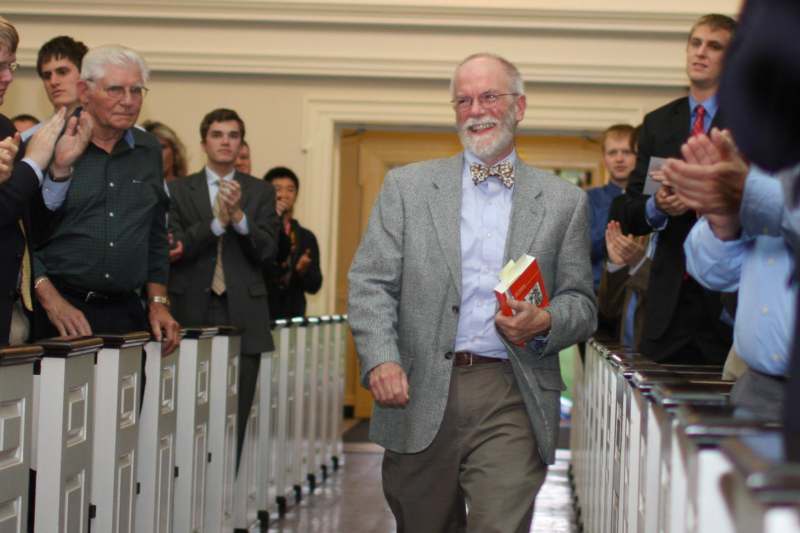 a man in a suit and bow tie walking down a hallway