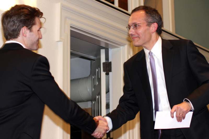 a man in suit shaking hands with another man in suit
