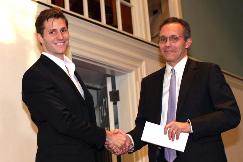 a man in suit shaking hands with another man in glasses