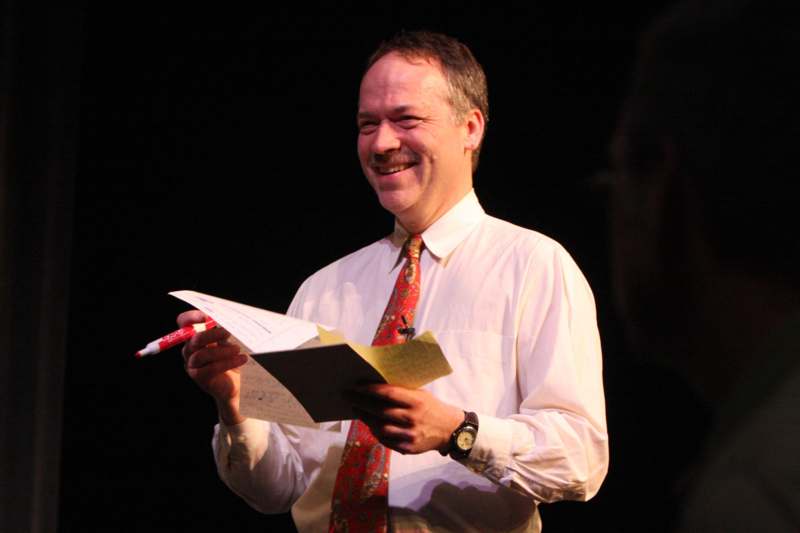 a man smiling and holding papers and pen