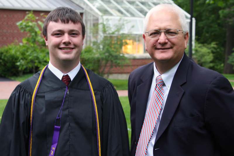 a man in a black robe and tie standing next to a man in a black robe and tie