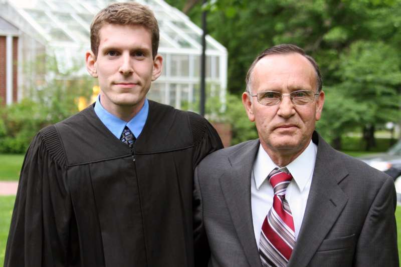 a man in a robe and tie standing next to a man in a suit