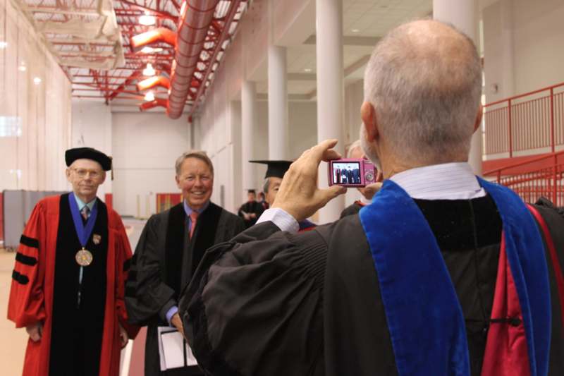 a man taking a picture of a man in graduation gown