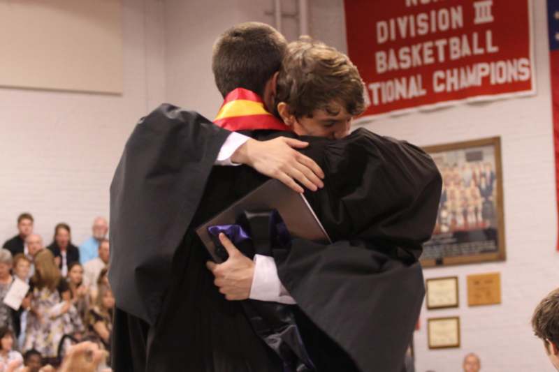 two men in graduation gowns hugging