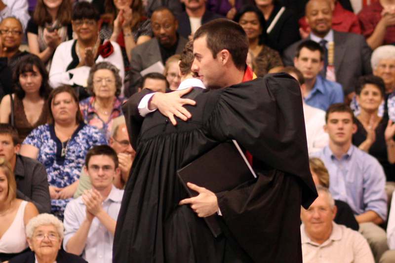 a man hugging another man in a graduation gown