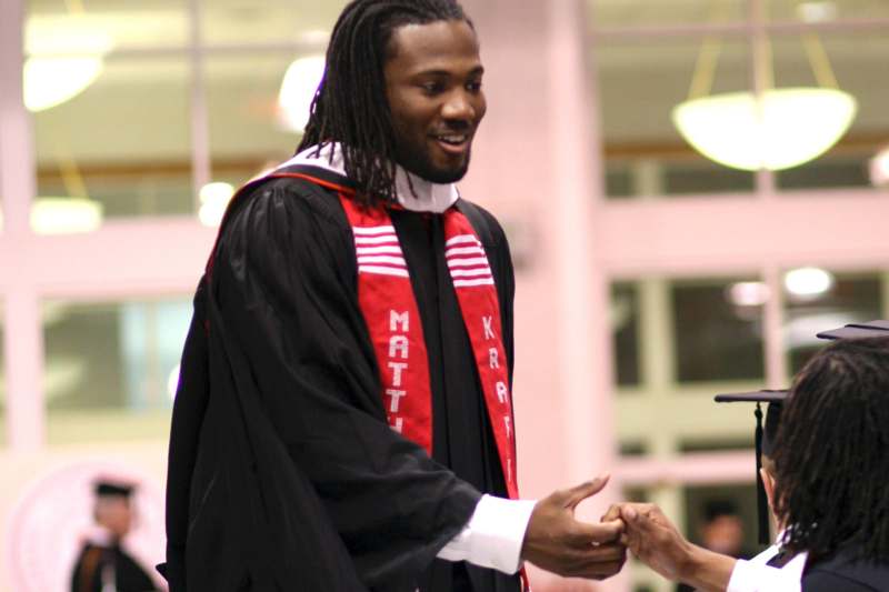 a man in a graduation gown shaking hands with a woman