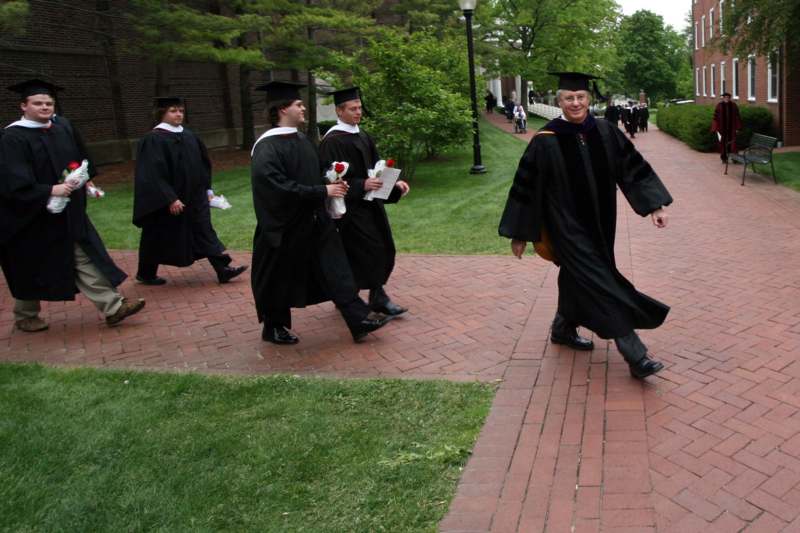 a group of graduates walking down a brick path