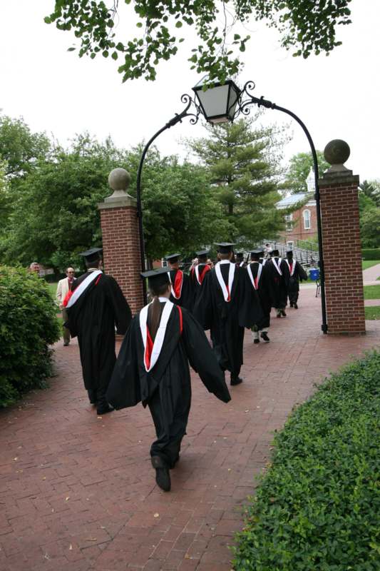 a group of people in graduation gowns walking down a brick path