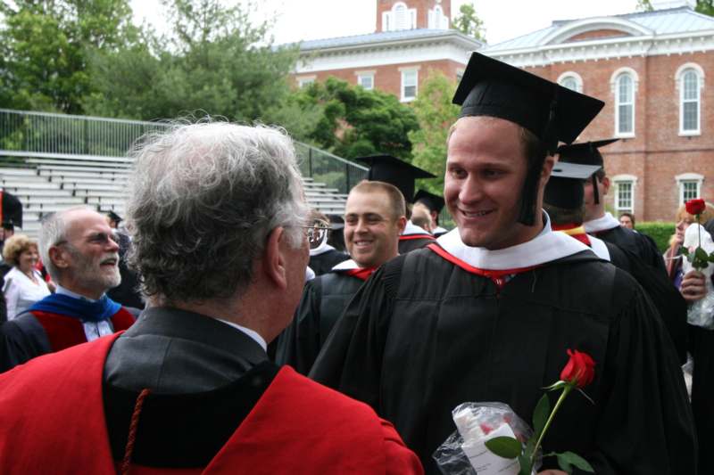 a man in cap and gown holding a rose