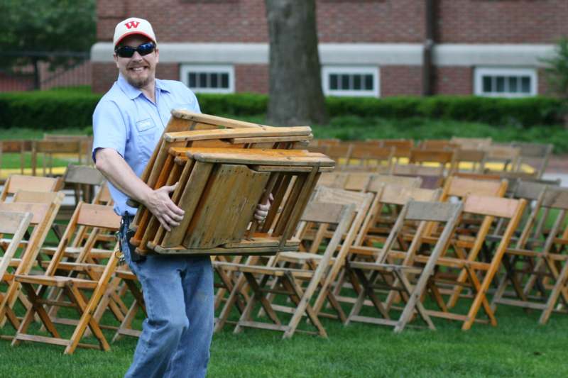 a man carrying a stack of chairs