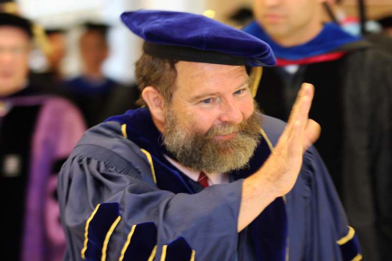 a man in a blue robe and cap waving