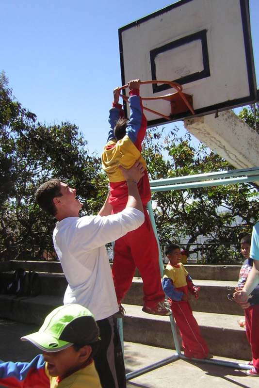 a man helping a child to swing a basketball hoop