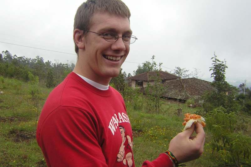 a man wearing glasses and a red shirt holding food