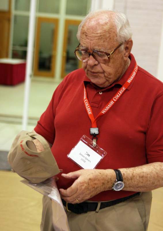 an old man wearing a red shirt and lanyard